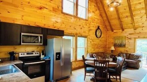 Un intérieur spacieux de chalet en bois, comprenant une cuisine, un coin repas et un salon.
