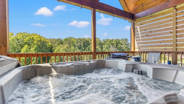 A hot tub with a wooden deck and a view of trees. - Daze Off - Natural Bridge, Luxury, Hot Tub, SUP Ky (Rogers)
