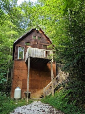 Un chalet rustique avec une façade en bois, un balcon et un escalier menant à un étage supérieur.