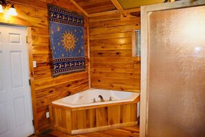 Interno di una baita in legno con una vasca da bagno angolare, una porta e un arazzo a parete.