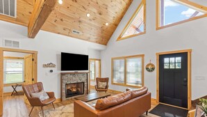 A spacious living room with a fireplace, leather sofa, and wooden flooring.