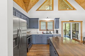 A modern kitchen with a large island, built-in appliances, and a view to the outdoors.