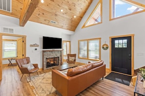 A spacious living room with a fireplace, leather sofa, and wooden flooring.