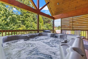 A hot tub with a wooden deck and a view of trees. - Hilltop Hideaway-NaturalBridge2m-Modern-HotTub (Rogers)