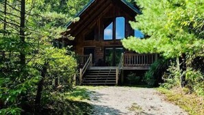 A cabin with a wooden exterior, a porch, and a gravel path leading to it. - Horseshoe Falls-RRG-Hot tub! (Rogers)