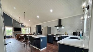 Cozinha moderna com ilha central, armários escuros e uma janela grande.
