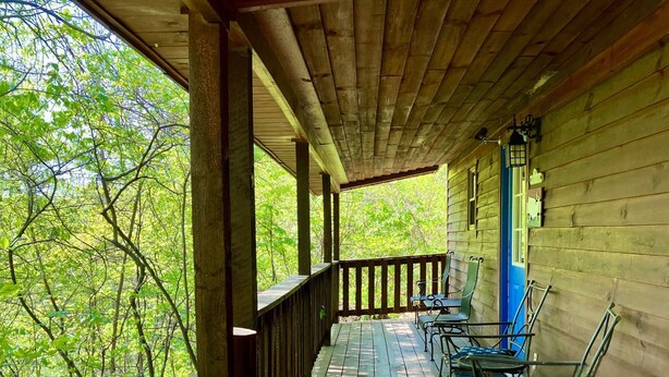 Un portico in legno con ringhiera, un tavolo e due sedie.