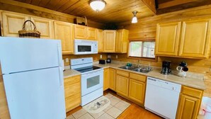 A compact kitchen with wooden cabinets, a refrigerator, a microwave, an oven, a sink, and a dishwasher. - Mountain Chalet |Hot Tub | Centrally Located | RRG (Campton)
