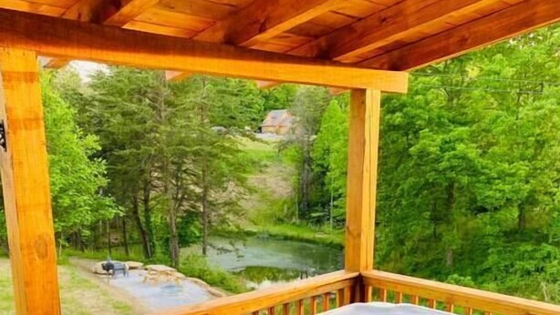 A hot tub on a wooden deck with a view of a forested area and a river.