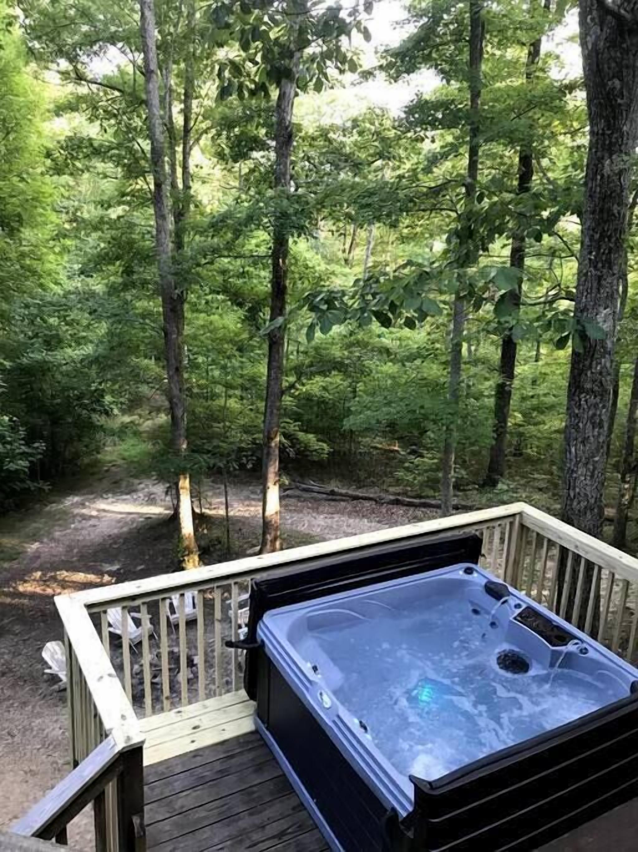 Een hottub op een houten terras, omringd door bos.
