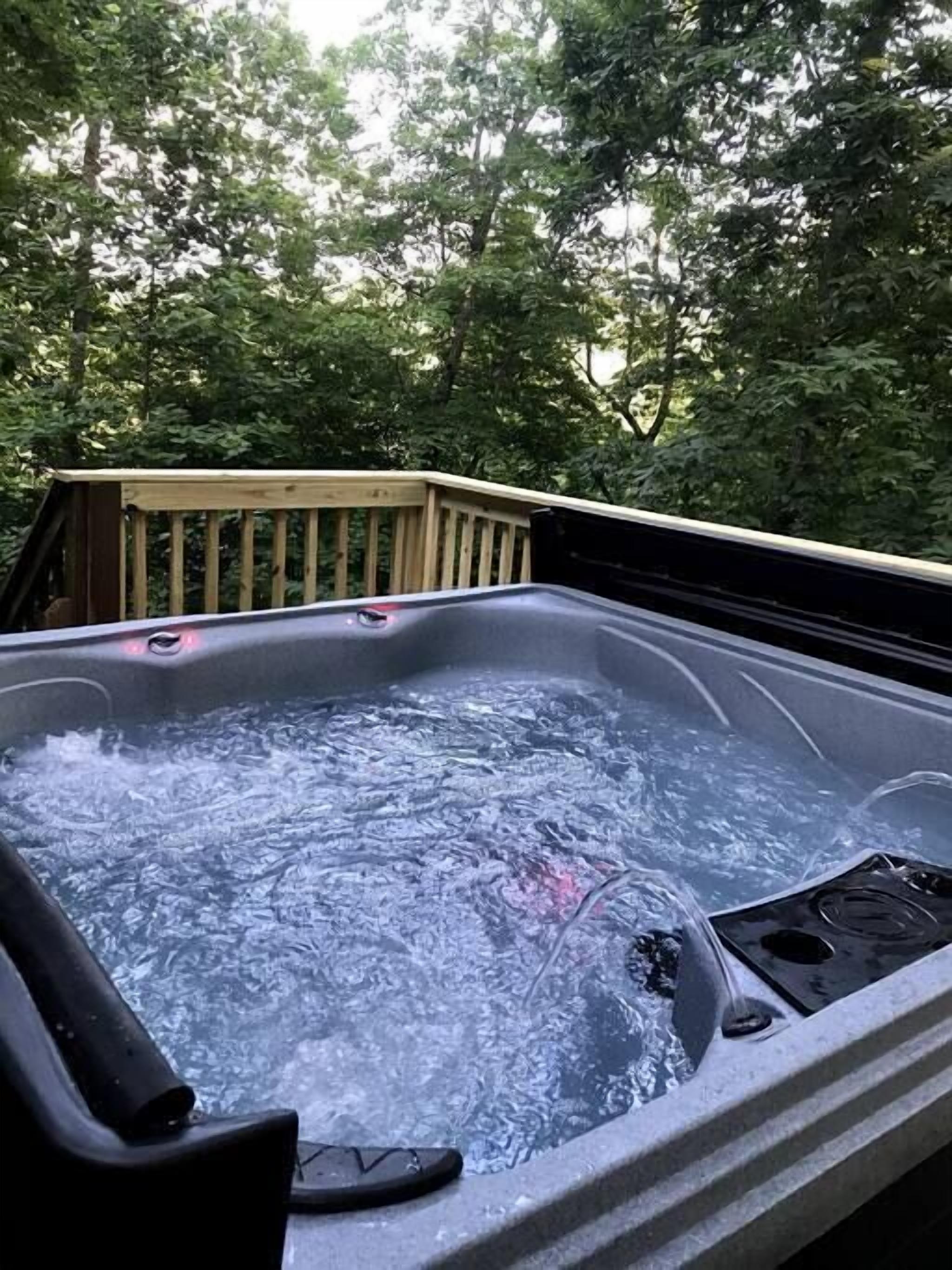 Een hottub op een terras, omgeven door bomen.