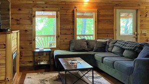 L’intérieur d’un chalet accueillant, avec un plafond en bois, un canapé, une table basse et une tête de cerf accrochée au mur.