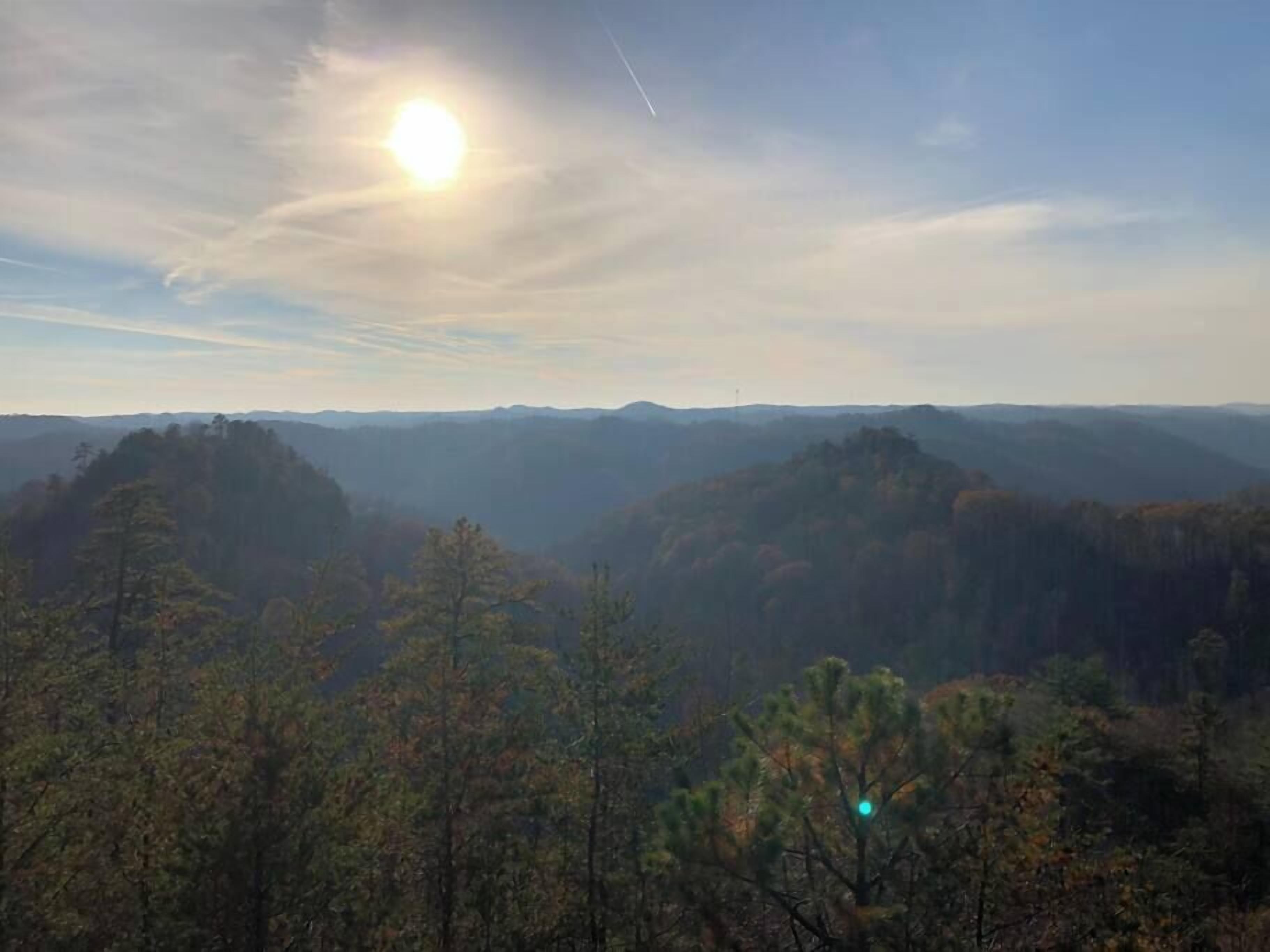 Un paisaje montañoso con cielo despejado y el sol brillando.
