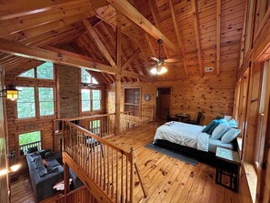 A cabin with a loft bedroom, a balcony, and a dining area.