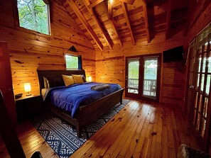 A wooden cabin bedroom with a bed, nightstands, and a window.