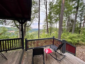 A wooden deck with a railing, two chairs, and a table.