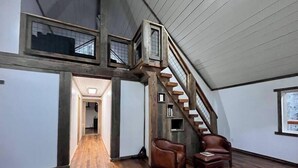 A spacious loft with a wooden staircase, a high ceiling, and a view of the city. - The Founder - Iconic Rockhouse Cabin! (Campton)