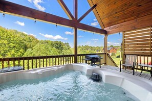 Un bain à remous sur une terrasse en bois, avec vue sur une forêt.