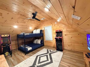 Une chambre confortable avec un lit superposé, un ventilateur de plafond, une console de jeux vidéo et un téléviseur.