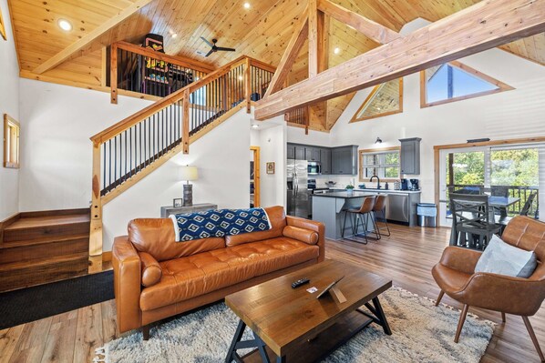 Un vaste espace de vie comprenant un canapé en cuir, une table basse en bois et un escalier avec des rampes en bois.
