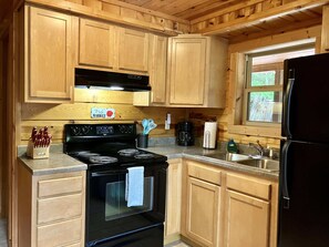 Enjoy cooking in this well-equipped kitchen with a sink, refrigerator, and black stove.