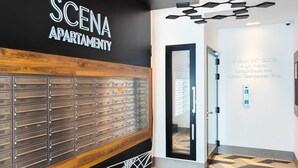 A modern lobby with a black and white color scheme, a wooden panel wall, and a glass door leading to an apartment.