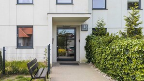Un bâtiment moderne, avec une plaque portant le numéro « 45 », un banc et une haie bien entretenue.