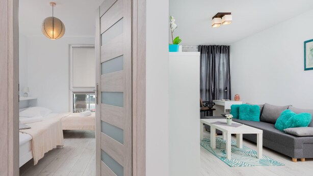 Une chambre moderne avec un lit, une table de chevet et un luminaire suspendu. La pièce est dotée d’un plancher en bois et d’une porte coulissante.