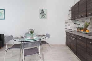 A modern kitchen with dark wood cabinets, a glass dining table, and a minimalist design. - Comfortable Apartment | Balcony, Parking, Workspace (Gdansk)