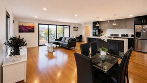 Un appartement moderne comprenant un coin repas, une cuisine, un salon et de grandes fenêtres.