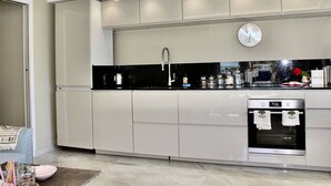 A modern kitchen with a black countertop, stainless steel appliances, and a clock on the wall.