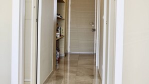 A narrow hallway with a closed door at the end, leading to a room.
