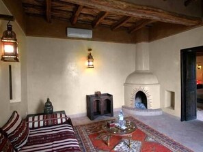 Une pièce avec une cheminée, un lit avec une literie à motifs et un tapis.