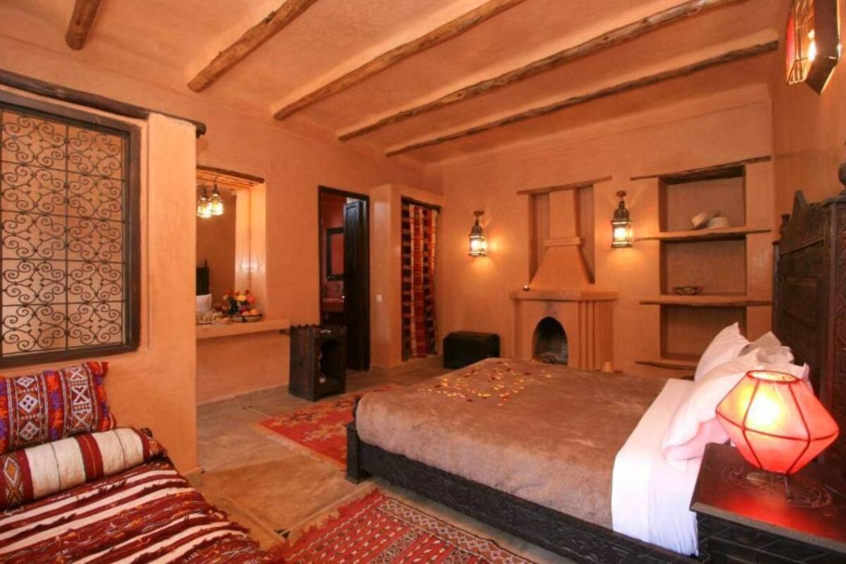 A cozy bedroom with a large bed, a fireplace, and a decorative wall.