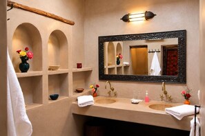 A bathroom with two sinks, a large mirror, and shelves with toiletries.