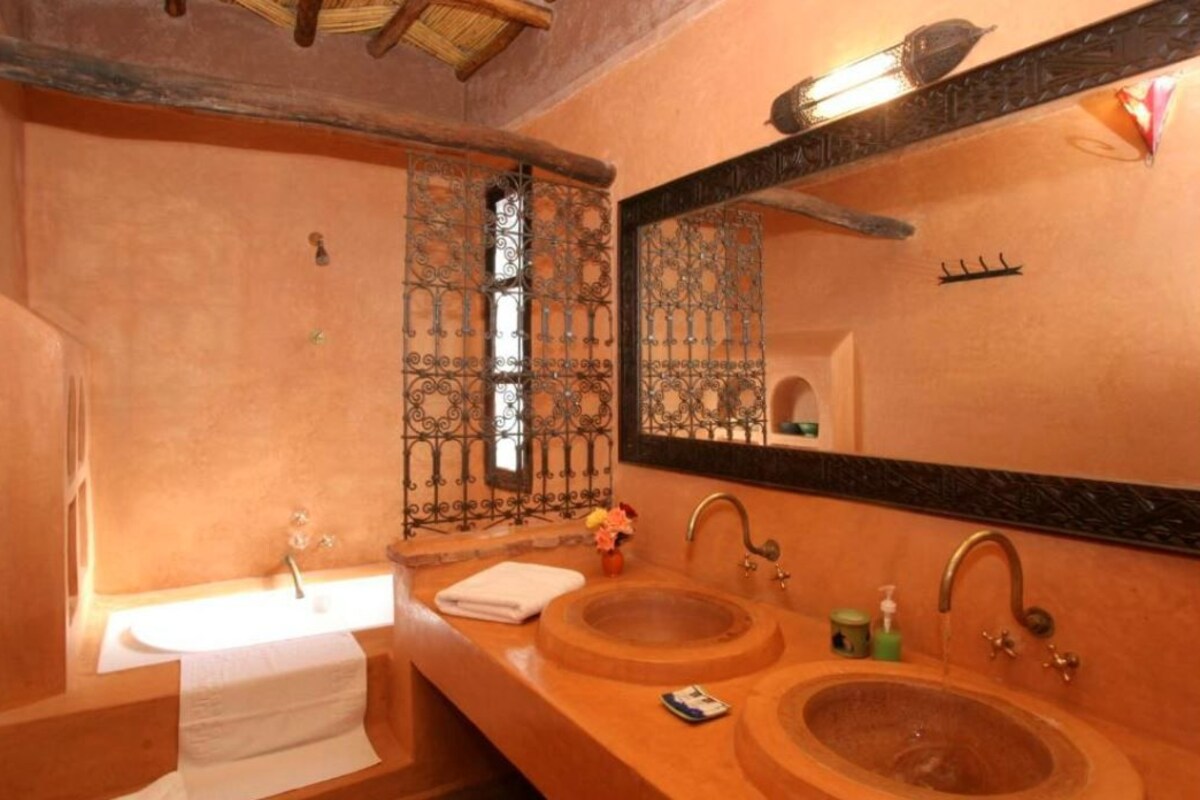 A bathroom with a large mirror, two sinks, and a window with decorative iron bars.