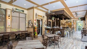 Ein geräumiges Restaurant mit hohen Decken, Holzböden und unterschiedlichen Sitzmöglichkeiten, darunter Tische und Stühle.