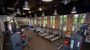 Ein Fitnessstudio mit Laufbändern, Krafttrainingsgeräten und einer großen Fensterfront.