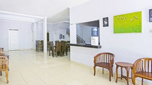 A spacious lobby with a reception desk, wooden chairs, a tiled floor, and artwork on the walls. - Hotel O Homestay Al Maidah (Depok)