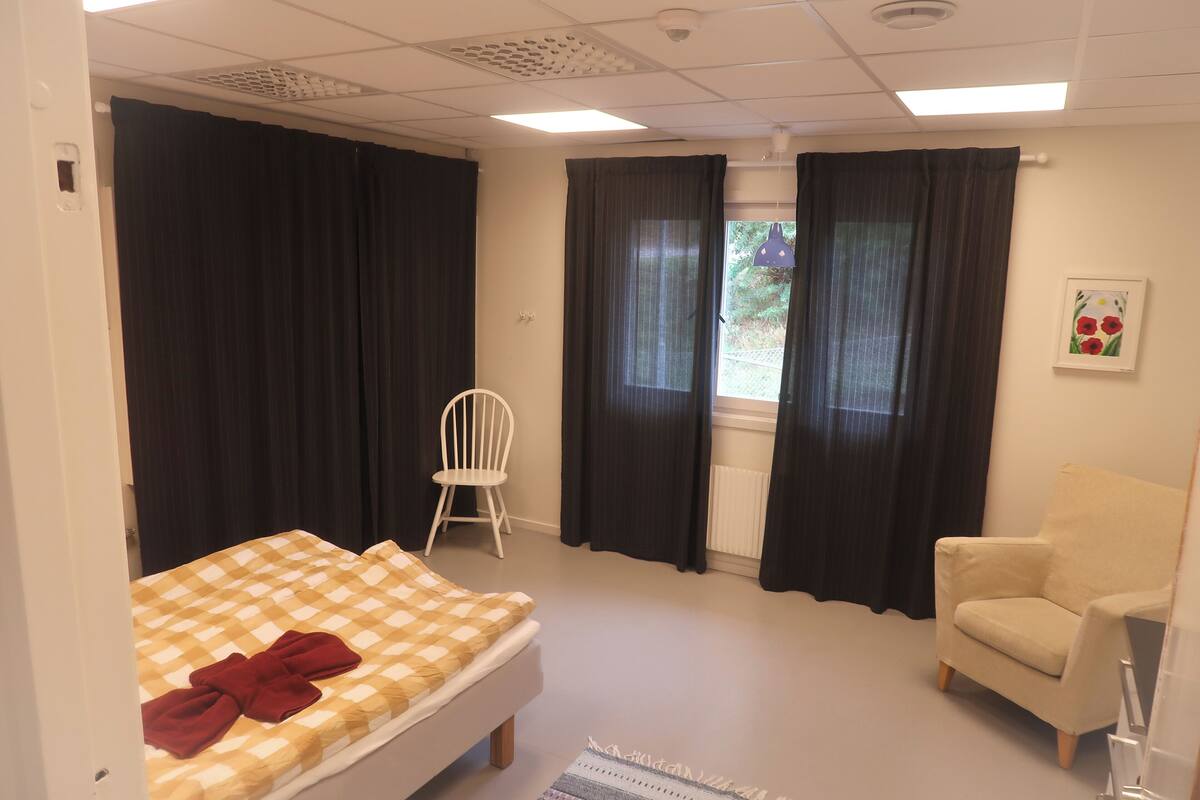 Une chambre à coucher avec un lit, une chaise et une fenêtre avec des rideaux.