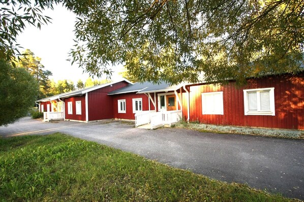 A row of red cabins with white trim, a gravel driveway, and surrounding greenery. - SKRÅ hostel- business bed & breakfast (Alno)