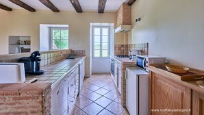 A kitchen with exposed wooden beams, a window, and a microwave. - Maison de Caractere à la Campagne (Saint-Geyrac)