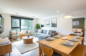 Een moderne woonkamer met een bank, salontafel en een eettafel gedekt voor een maaltijd.