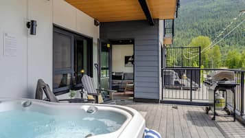 Un jacuzzi en una terraza de madera con vista a las montañas.