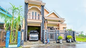 A two-story house with a car parked in the driveway.