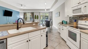 A modern kitchen with white cabinets, a stainless steel sink, and a microwave. - 9817 Cristalino Way #102 (Fort Myers)