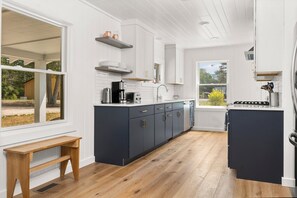 Una cocina moderna con armarios oscuros, encimeras blancas y un banco de madera.