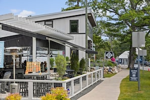 A modern building with outdoor seating, a covered patio, and a sign indicating a Kid's Drop-In Art Class.