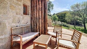 A rustic outdoor seating area with a stone wall, wooden benches, and a table. - Location Saisonnière Atypique à Porticcio (PORTICCIO)
