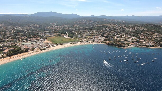 An aerial view of a coastal town with a beach, boats, and mountainous terrain in the background. - Location Saisonnière Atypique à Porticcio (PORTICCIO)